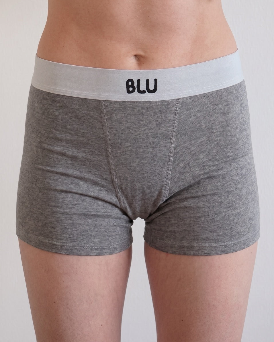 A close-up of a person wearing heather gray boxer briefs with a light gray waistband featuring the black text 'BLU'.