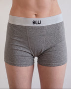 A close-up of a person wearing heather gray boxer briefs with a light gray waistband featuring the black text 'BLU'.